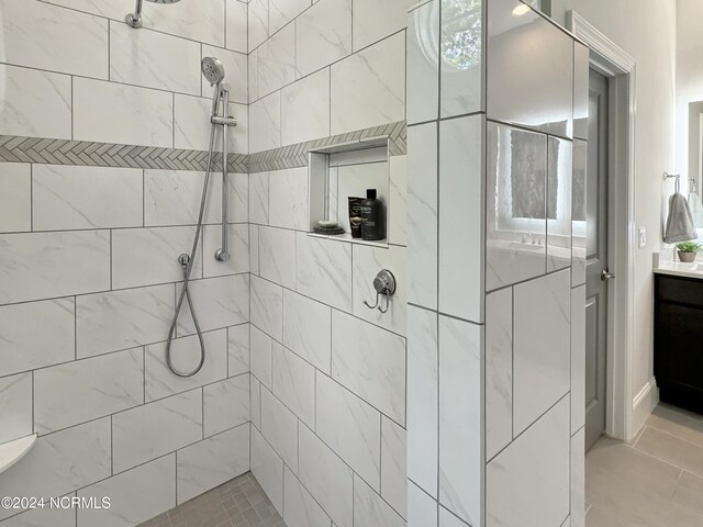 bathroom featuring vanity, tiled shower, and tile patterned flooring