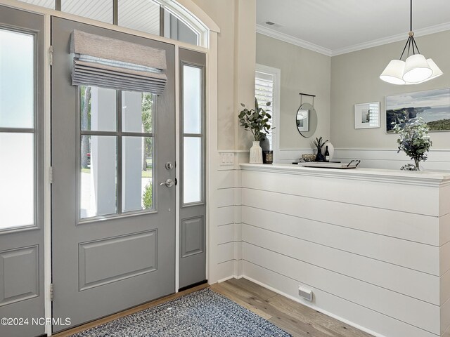 doorway featuring crown molding, a chandelier, and hardwood / wood-style flooring