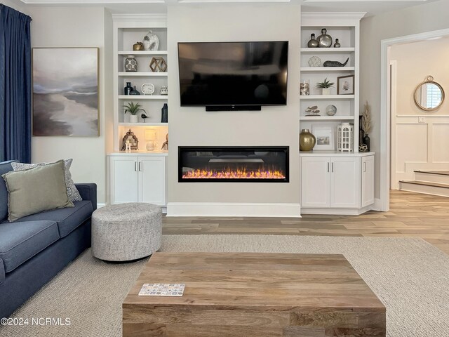 living room featuring light wood-type flooring and built in shelves