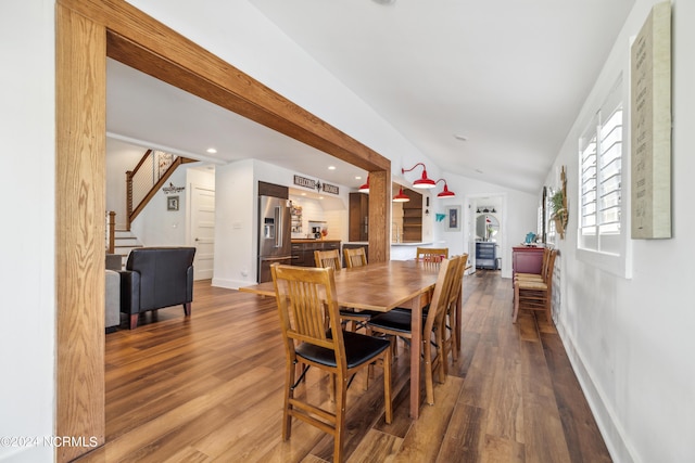 dining room with lofted ceiling, stairway, wood finished floors, and baseboards