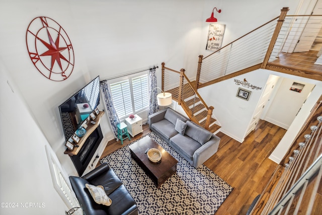 living room featuring dark wood-type flooring, stairway, a high ceiling, and baseboards