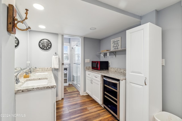 kitchen featuring dark wood-type flooring, white cabinetry, a sink, light stone countertops, and beverage cooler