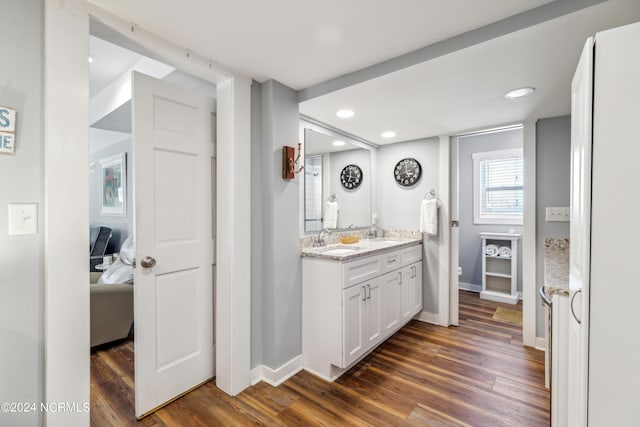 ensuite bathroom with ensuite bathroom, a sink, wood finished floors, baseboards, and double vanity