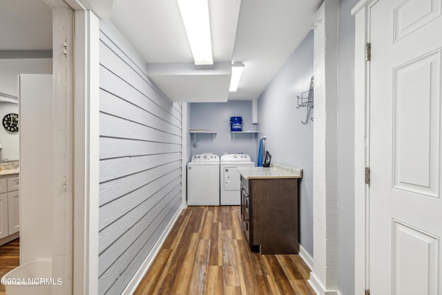 washroom featuring wooden walls, dark wood-type flooring, laundry area, and washer and dryer