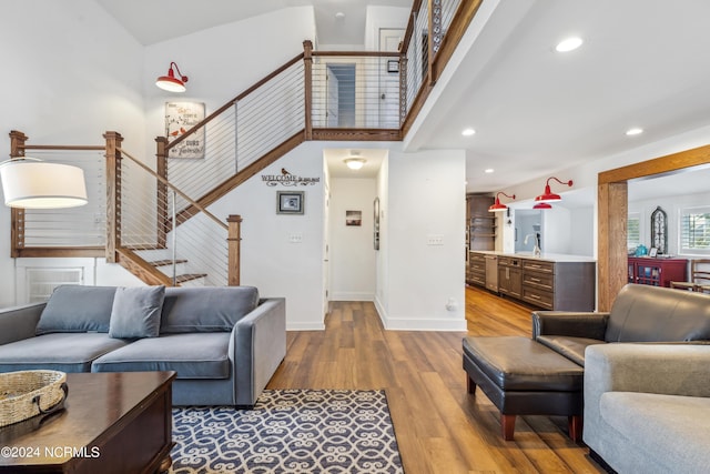 living room with indoor wet bar, recessed lighting, light wood-style floors, baseboards, and stairs