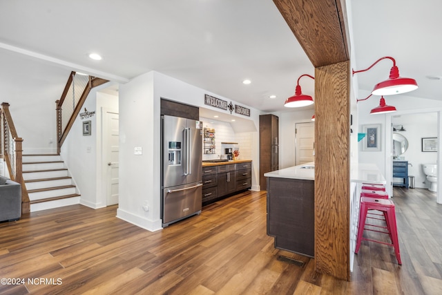 kitchen featuring light countertops, high quality fridge, dark wood-style flooring, and dark brown cabinets