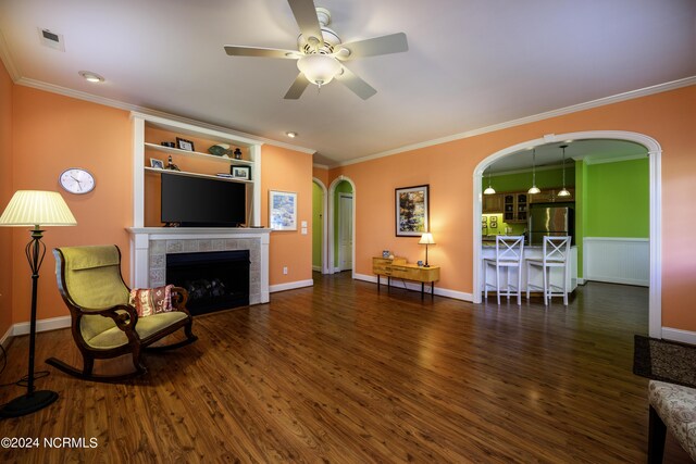 living room featuring dark hardwood / wood-style flooring, a fireplace, ornamental molding, and ceiling fan