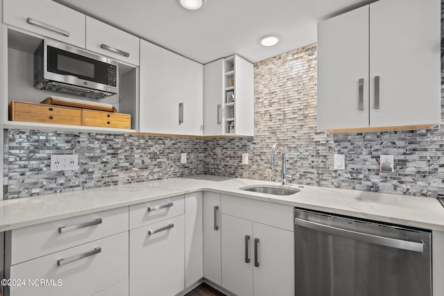 kitchen featuring light stone counters, decorative backsplash, stainless steel appliances, and sink