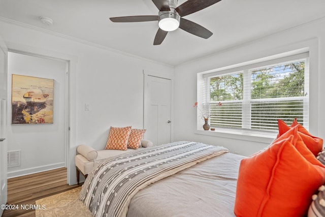 bedroom with ceiling fan, ornamental molding, and wood-type flooring