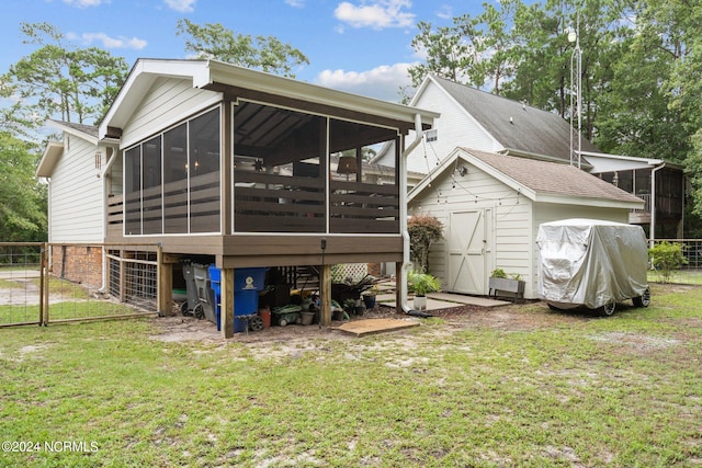 back of property with a sunroom, a storage shed, and a lawn