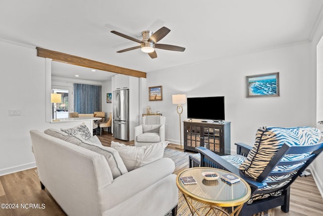 living room with ceiling fan, light hardwood / wood-style flooring, beam ceiling, and ornamental molding