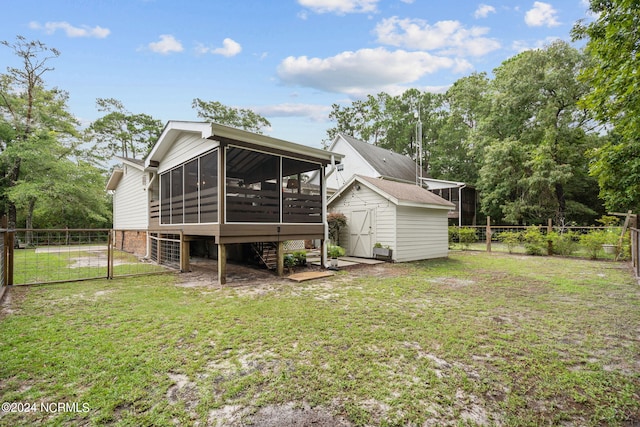 back of property with a lawn, a sunroom, and a shed