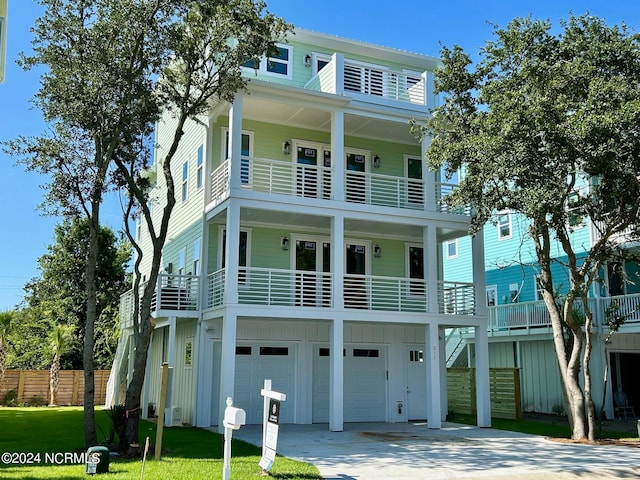 coastal inspired home with a front yard, a garage, and a balcony