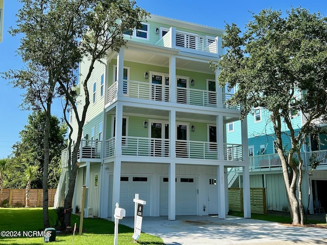 coastal home with a garage, concrete driveway, fence, a front lawn, and board and batten siding