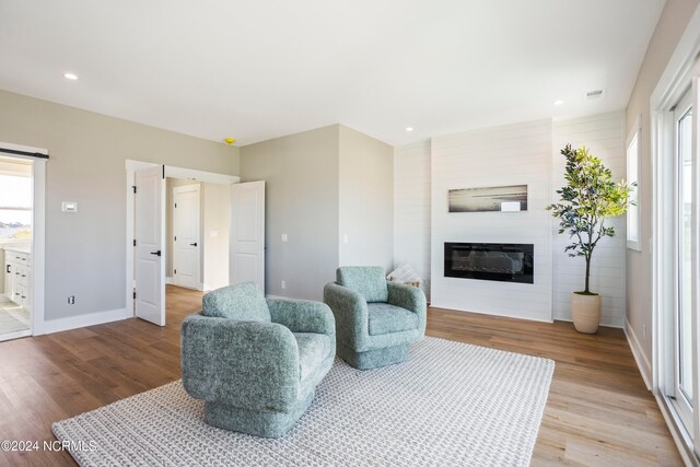 living room with a fireplace, light wood-type flooring, and plenty of natural light