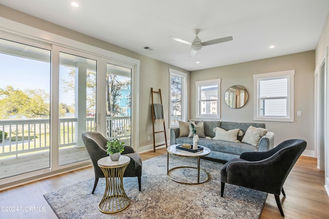 living room featuring ceiling fan, light wood-type flooring, and a wealth of natural light