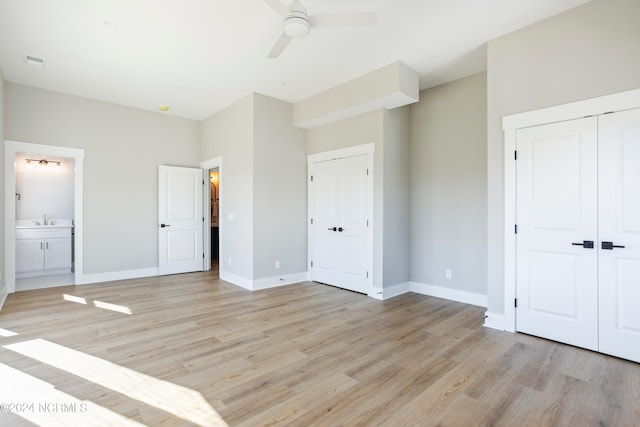 unfurnished bedroom with ensuite bathroom, sink, light wood-type flooring, a closet, and ceiling fan