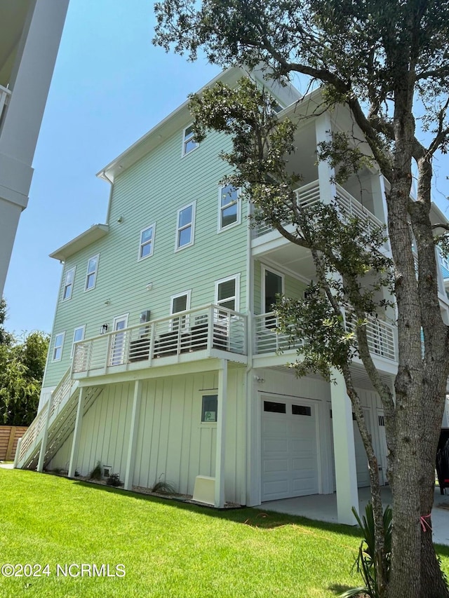 back of house featuring a balcony, a garage, and a lawn