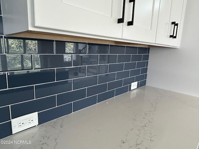 interior details featuring white cabinetry and backsplash