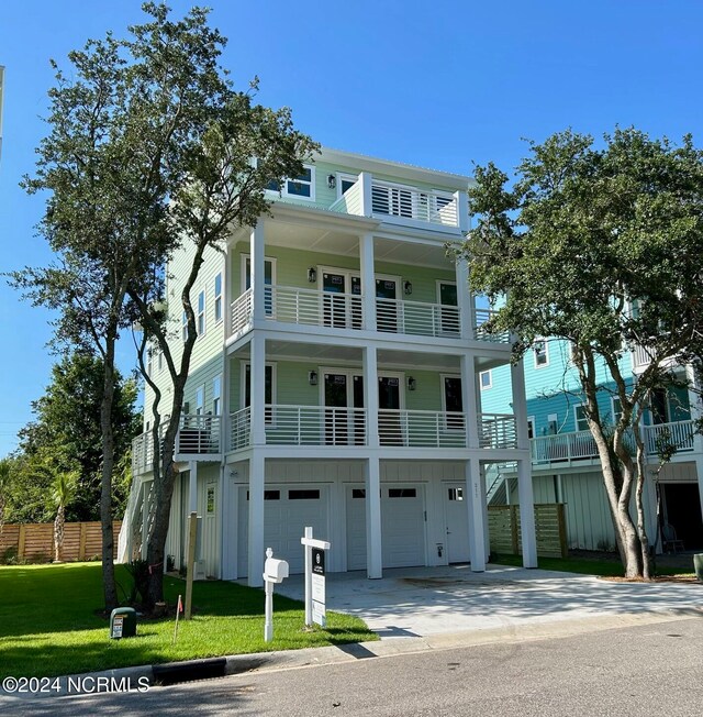 view of front of house featuring a front lawn, a garage, and a balcony