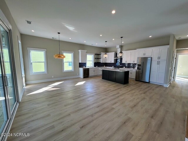 kitchen featuring stainless steel fridge, white cabinetry, pendant lighting, and a center island