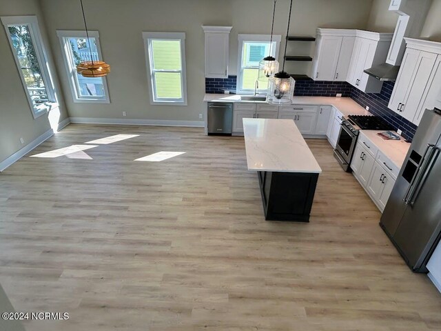 kitchen featuring a center island, appliances with stainless steel finishes, decorative backsplash, and pendant lighting