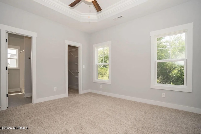 unfurnished bedroom with carpet, a spacious closet, and multiple windows