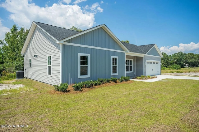 view of front of property with a garage, cooling unit, and a front yard