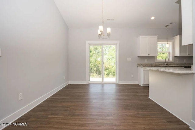 kitchen featuring dark hardwood / wood-style flooring, decorative light fixtures, white cabinets, an inviting chandelier, and light stone counters