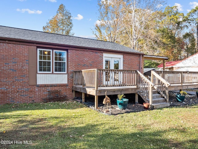 back of property with a lawn, a wooden deck, and french doors