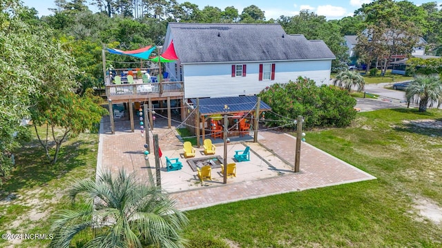 rear view of property with a deck, a yard, and roof with shingles