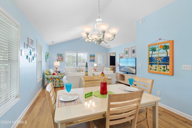 dining room with an inviting chandelier, baseboards, vaulted ceiling, and light wood-style floors