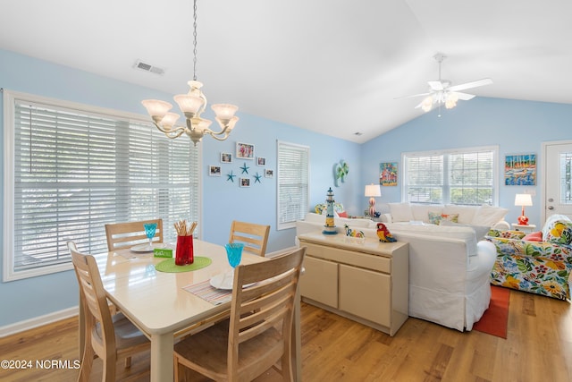 dining space featuring vaulted ceiling, ceiling fan with notable chandelier, and light wood-type flooring