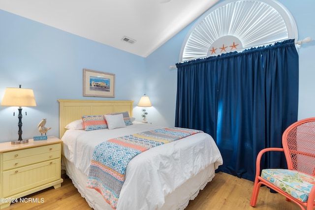 bedroom with lofted ceiling, light wood-type flooring, and visible vents