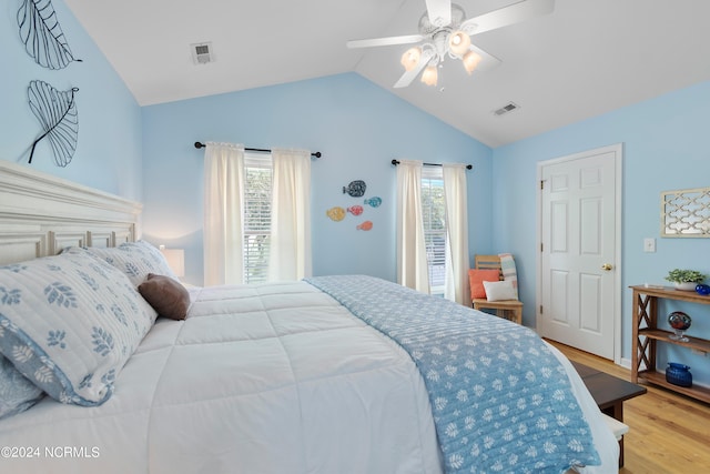 bedroom featuring vaulted ceiling, light hardwood / wood-style flooring, multiple windows, and ceiling fan