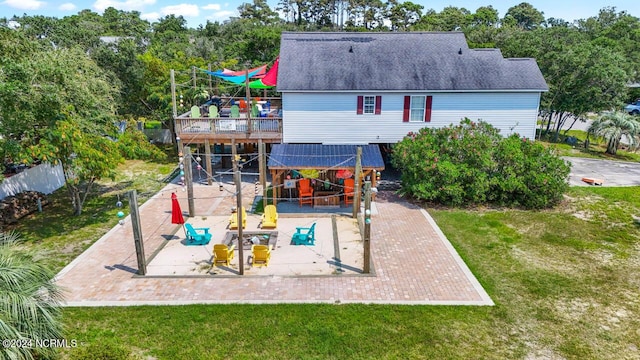 rear view of property featuring a patio area, roof with shingles, a deck, and a yard