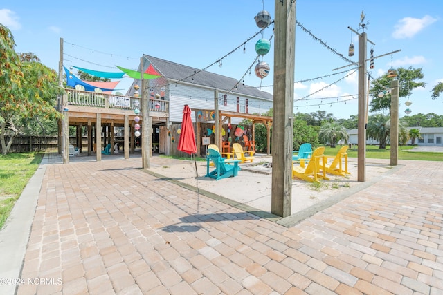 communal playground featuring an outdoor fire pit, fence, and a wooden deck