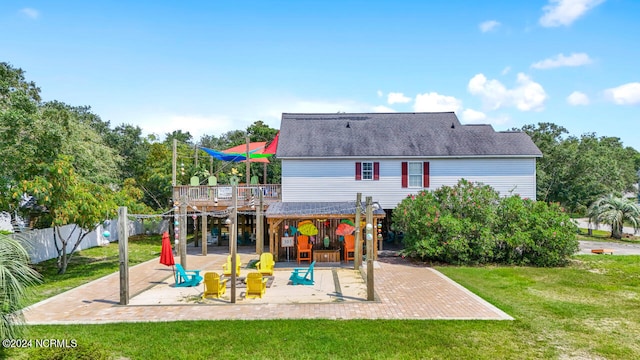 back of property with a wooden deck, a patio, and a lawn