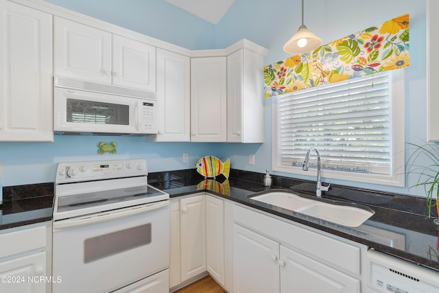 kitchen featuring white appliances, dark stone countertops, a sink, and white cabinetry