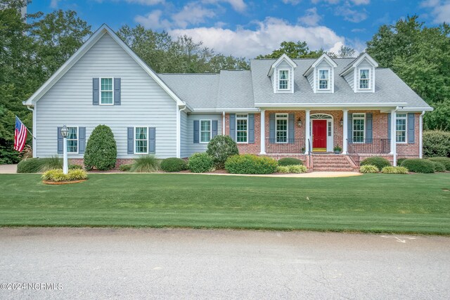 cape cod home featuring a front lawn and covered porch