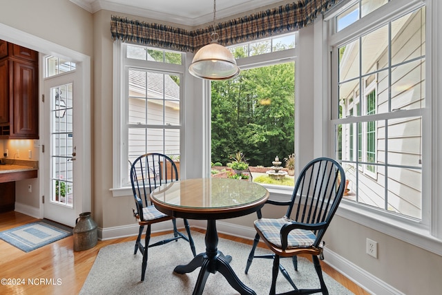 dining space with light wood finished floors, baseboards, and ornamental molding