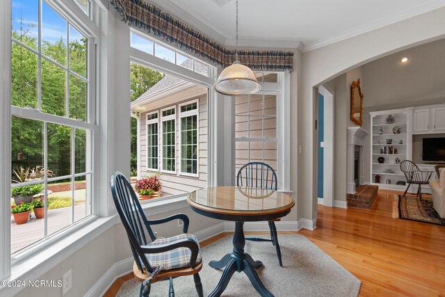 dining area featuring a wealth of natural light, a fireplace, light hardwood / wood-style floors, and ornamental molding