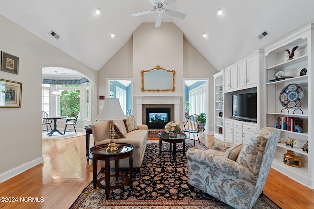 living room featuring a premium fireplace, ceiling fan, high vaulted ceiling, and light hardwood / wood-style floors