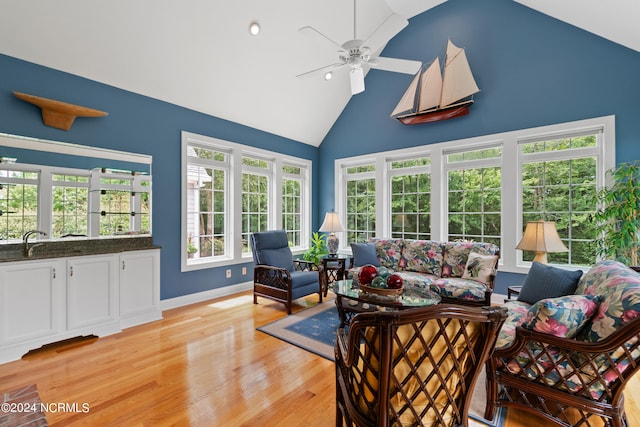 living room with high vaulted ceiling, ceiling fan, light wood-style flooring, and baseboards