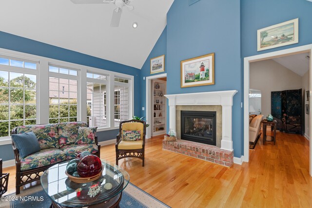 living room with a fireplace, high vaulted ceiling, plenty of natural light, and wood-type flooring