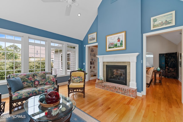 living room with a fireplace, a ceiling fan, wood finished floors, high vaulted ceiling, and baseboards