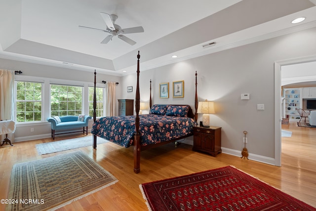 bedroom with a tray ceiling, baseboards, light wood finished floors, and recessed lighting