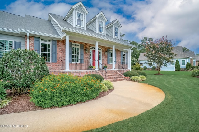 new england style home featuring a porch and a front lawn