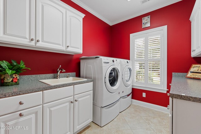 clothes washing area featuring cabinets, light tile patterned floors, washing machine and clothes dryer, crown molding, and sink