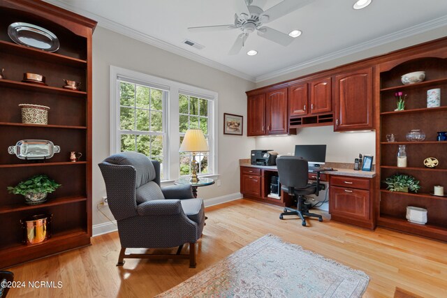 home office with light wood-type flooring, built in desk, ornamental molding, and ceiling fan